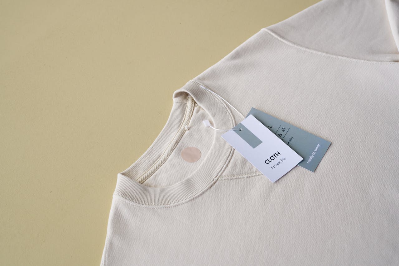 Minimalist beige sweatshirt displayed with tags on a yellow background, perfect for e-commerce.